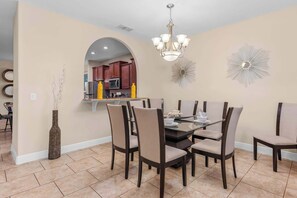 A dining area with a round table, six chairs, a vase, and a chandelier. - Resort Villa w/ Private Pool & Family Fun (Davenport)