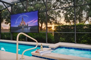 A pool area with a view of a castle, a television screen, and a bottle of champagne. - Resort Villa w/ Private Pool & Family Fun (Davenport)
