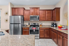 A kitchen with wooden cabinets, stainless steel appliances, granite countertops, and a built-in oven.