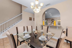 A dining area with a glass table, chairs, and a chandelier.