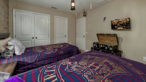 Una camera da letto con due letti, un comò, una televisione e un quadro appeso al muro.
