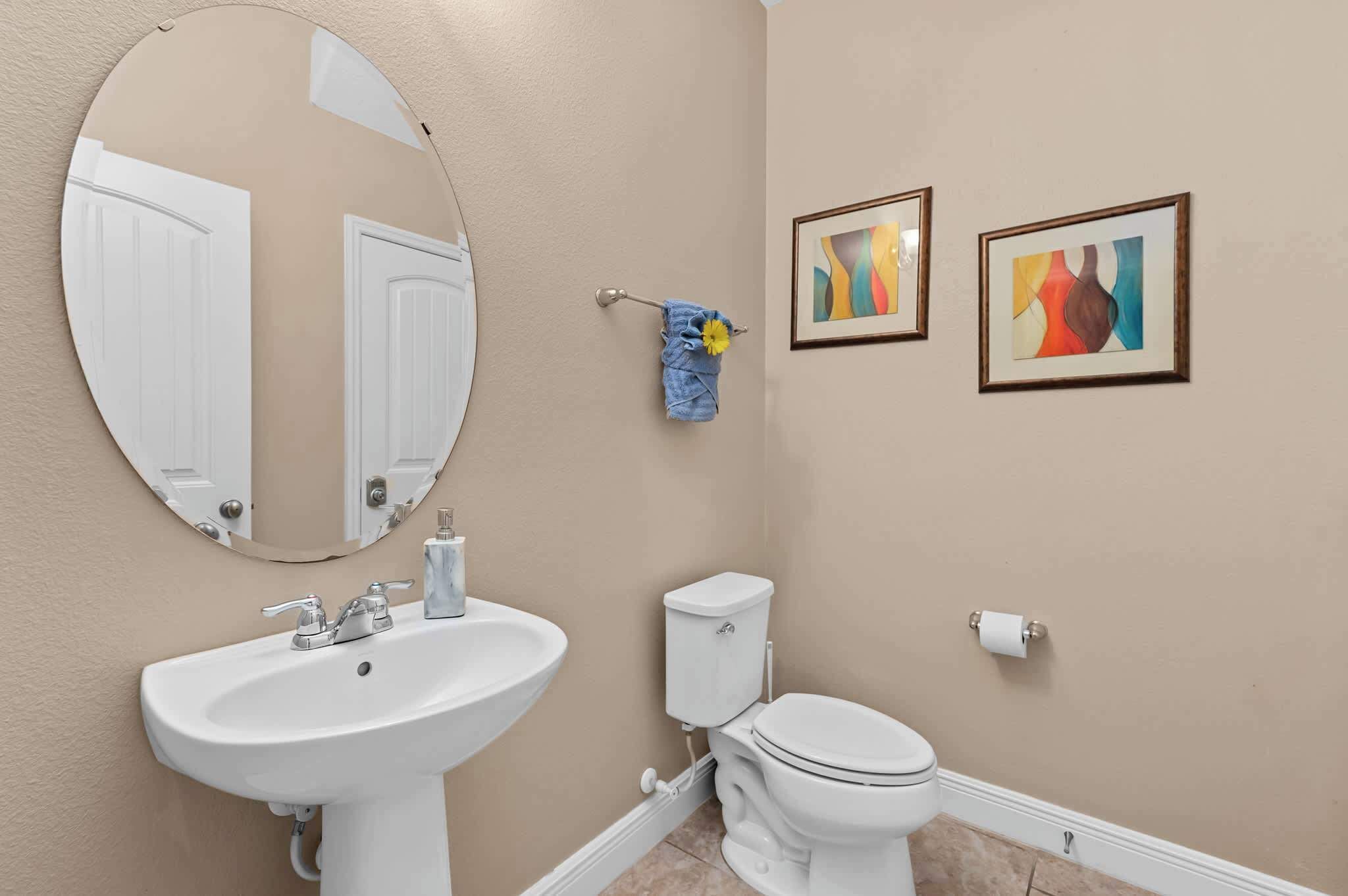 A bathroom with a sink, toilet, and two framed artworks on the wall.