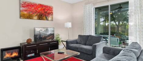 A living room with a fireplace, a sofa, a coffee table, and a TV.
