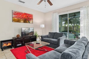 A living room with a fireplace, a sofa, a coffee table, and a TV.