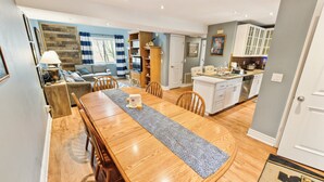 Amplia sala de estar con una mesa de comedor de madera, un sofá y una cocina al fondo.