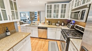 Una cocina moderna con armarios blancos, lavavajillas, estufa y microondas.