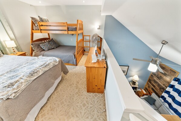 Cozy bedroom with a bunk bed and a desk area featuring a computer and fan.