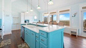 A kitchen with a large island, white cabinets, and a view to the outside. - Sunset Bliss 4 Bedroom Home (Port Bolivar)