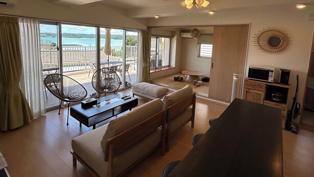 Un vaste espace de vie comprenant un canapé, une table à manger et une vue sur la mer.