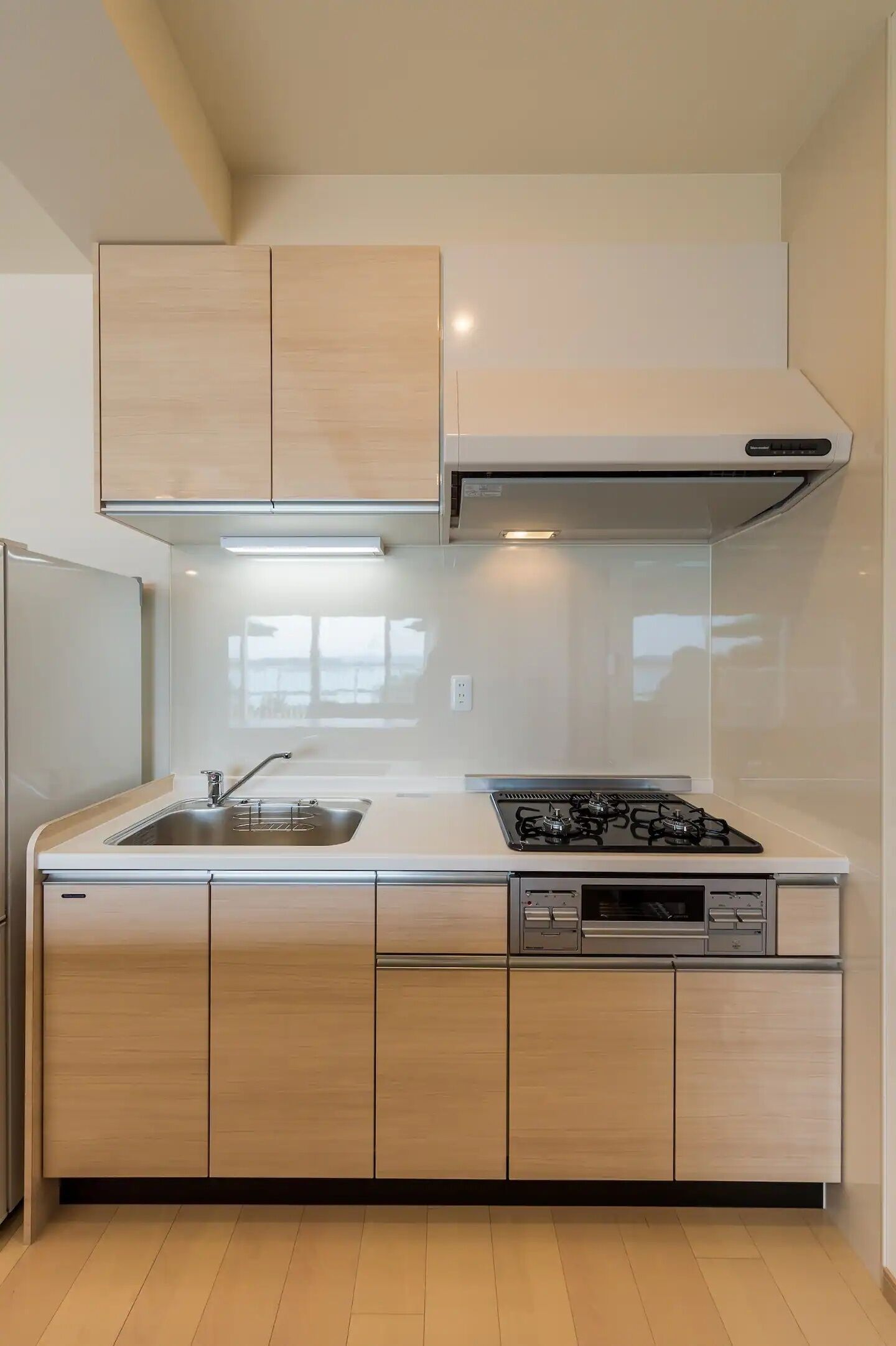 Een moderne keuken met lichte houtkleurige kastjes, een roestvrijstalen spoelbak en een gasfornuis.