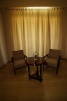 Una habitación con dos sillones y una mesita redonda con un jarrón de flores.