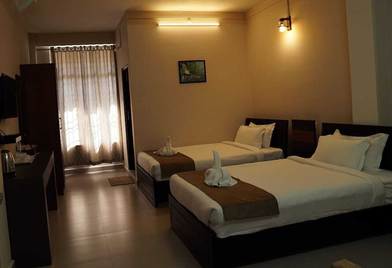 A hotel room with two beds, a desk, a television, and a painting on the wall.