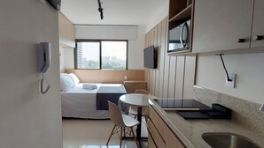 Una habitación de hotel compacta con cama, una mesita, microondas y teléfono.