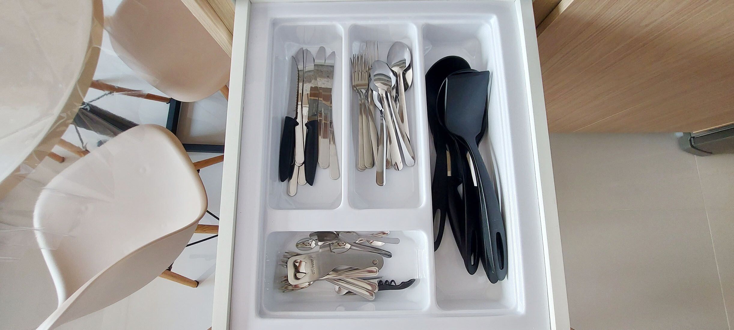 A drawer with utensils and keys.