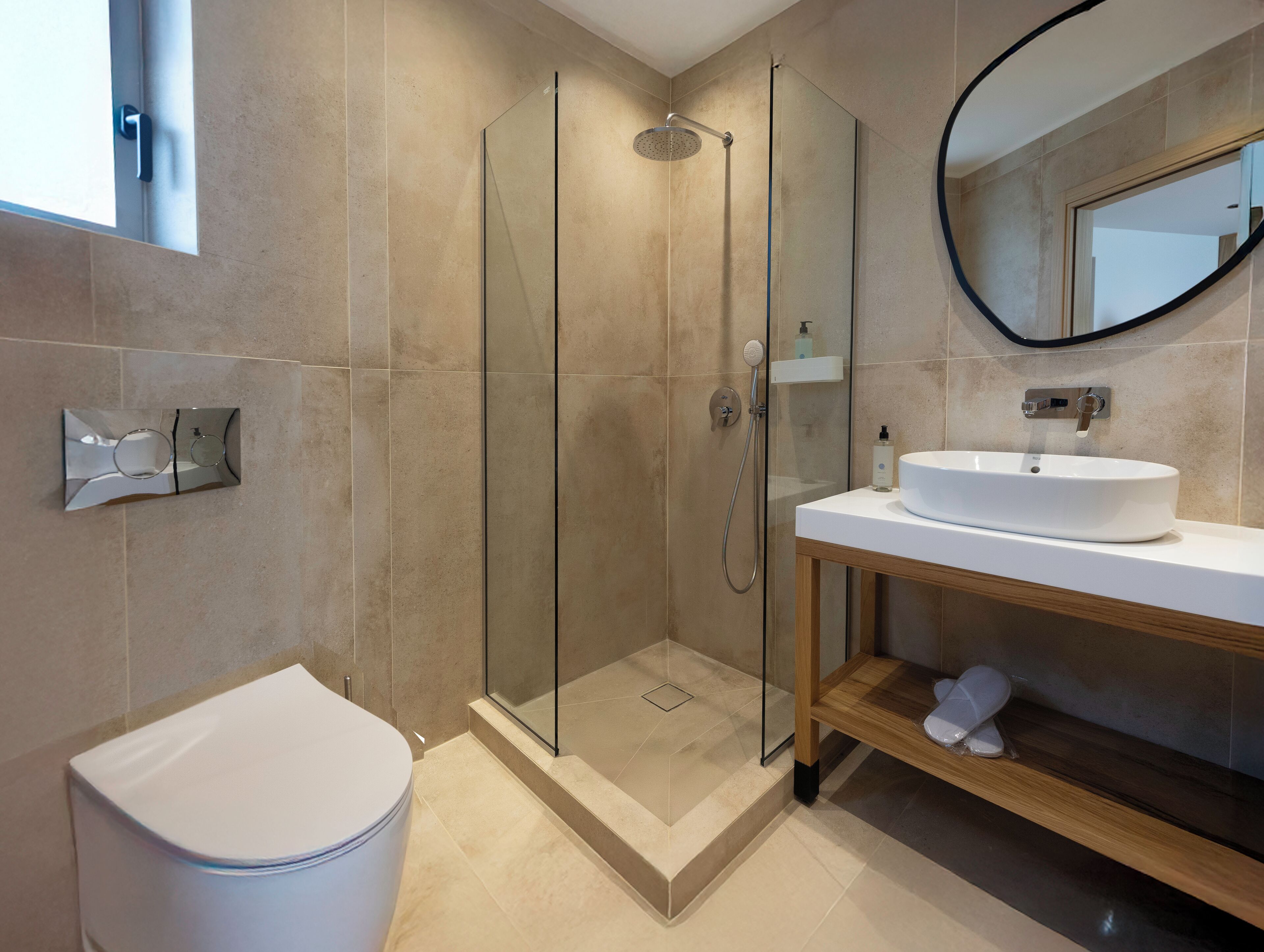 A modern bathroom with a glass-enclosed shower, a white toilet, and a sink with a wooden vanity.