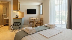 Una habitación de hotel con cama, escritorio, silla, televisión y ventana.