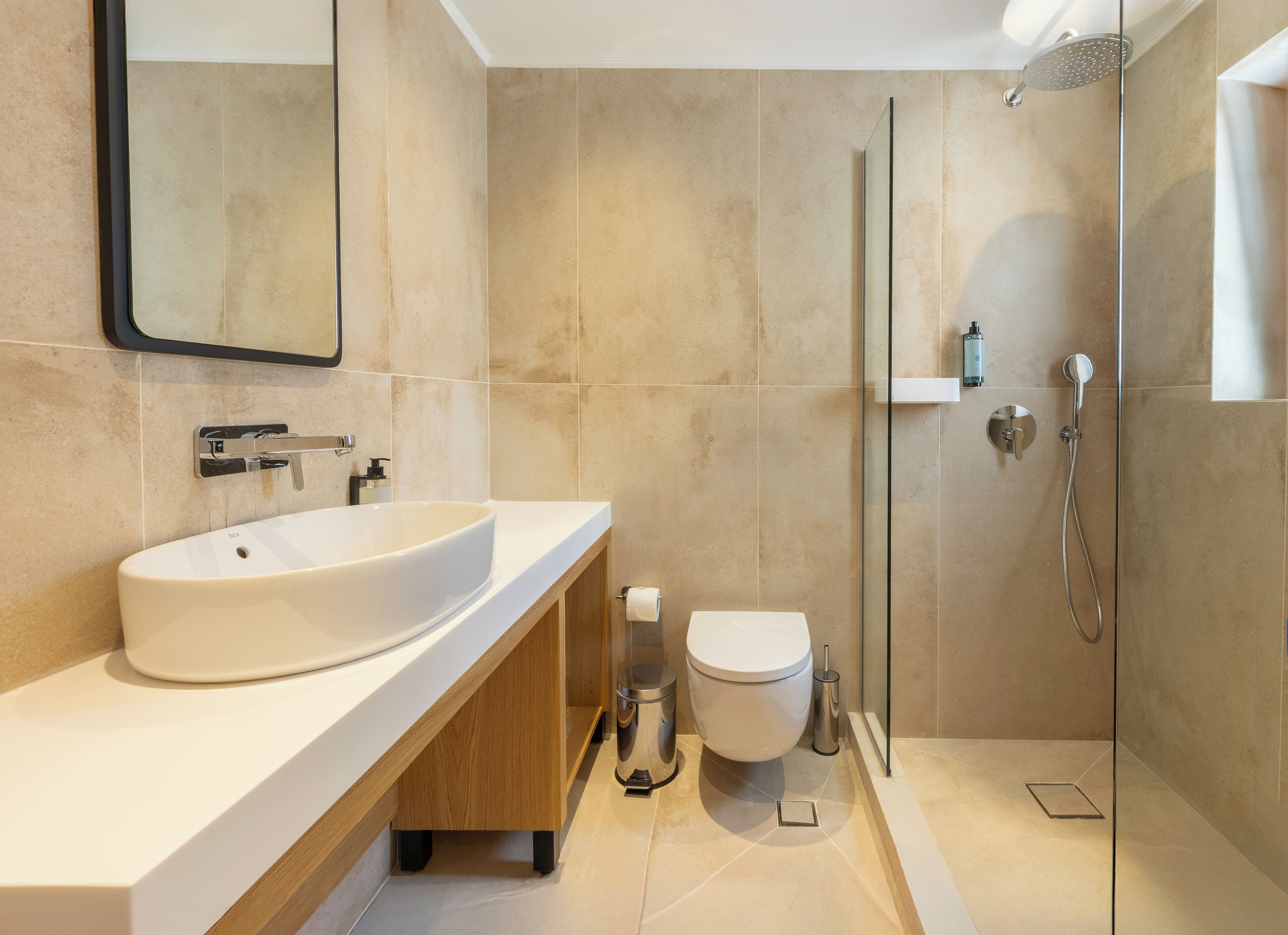 Een moderne badkamer met een groot wastafel, toilet en glazen douchecabine.