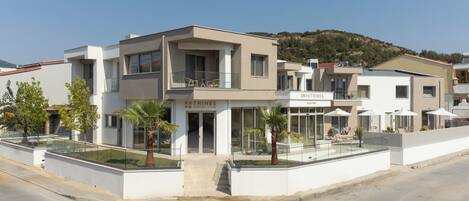 A modern multi-story building with a reception area, outdoor seating, and a landscaped terrace.