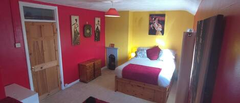 A bedroom with a bed, a dresser, a red rug, and a door.