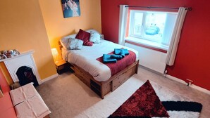 Une chambre à coucher avec un lit, une fenêtre avec des rideaux, une cheminée et un tapis.