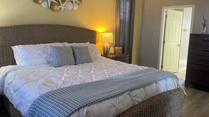 A neatly made bed with white and striped pillows, a wicker headboard, and a decorative wall with starfish and seashells.