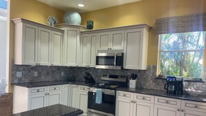 A kitchen with white cabinets, a microwave, a stove, and a coffee maker.