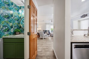 A hallway with a kitchen area featuring a countertop, sink, and a dishwasher. There is a door leading to a living area with a chair and a table. - 3BR Near Beach | Pool | 2 Private Outdoor Spaces (Myrtle Beach)