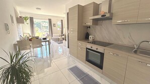 Een moderne keuken met een ingebouwde oven, een spoelbak en een eethoek met een tafel en stoelen.
