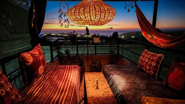 A balcony with a view of the sunset, a hanging dreamcatcher, and a hammock.