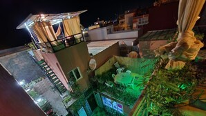 A rooftop garden with a dining area, a small pool, and a staircase leading to an upper level.