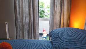 Een bed met een blauwe sprei en een klein tuinkabouterbeeldje op een vensterbank.