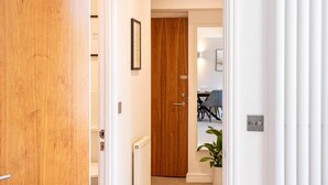 A hallway leading to a dining area with a wooden door, a radiator, and a potted plant.