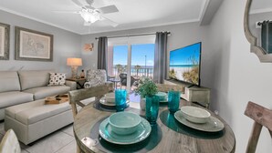 A living room with a sofa, a dining table set with plates and glasses, a TV, and a ceiling fan.
