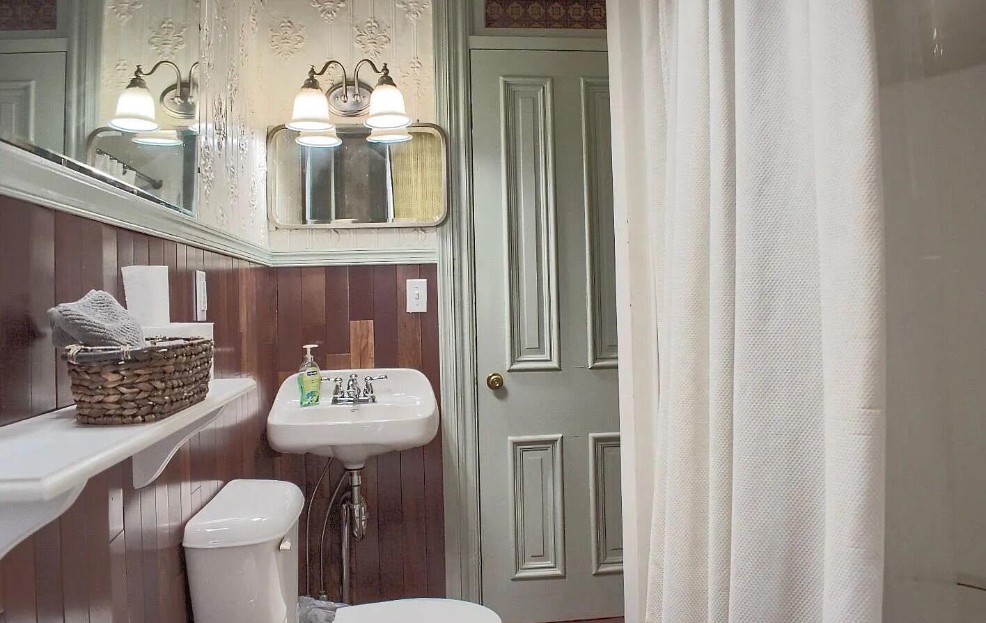 A bathroom with a white sink, a mirror above it, and a wooden vanity.