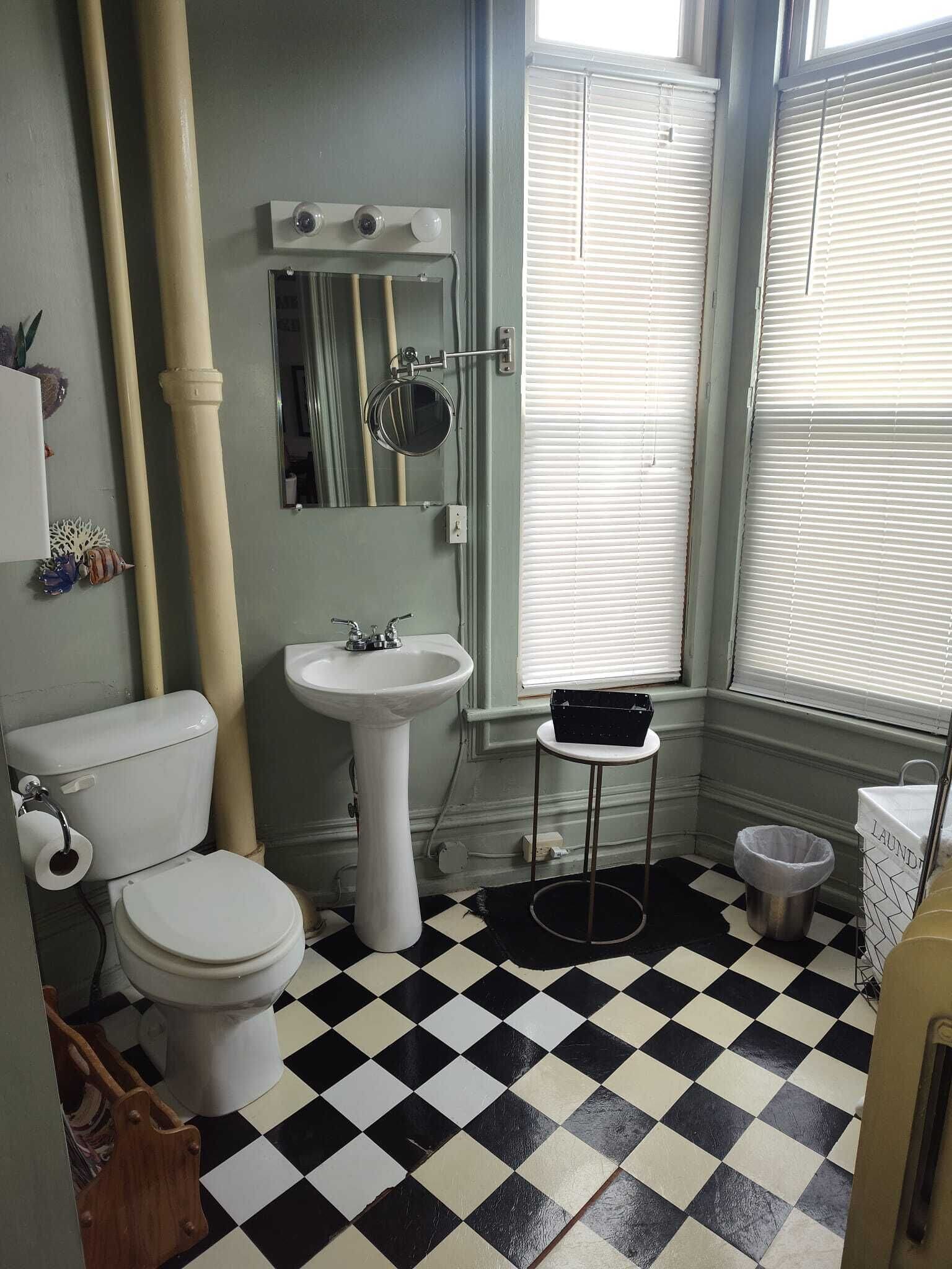 Ein Badezimmer mit Toilette, Waschbecken und einem Fenster mit Jalousien.