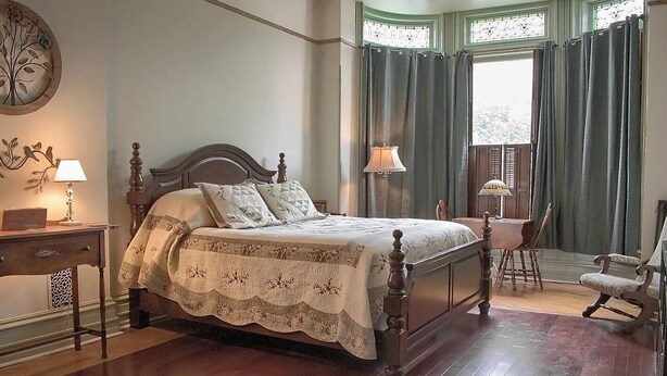 A traditional bedroom with a four-poster bed, a desk with a lamp, a chair, and a window with curtains. - Shamokin Bed and Breakfast (Shamokin)