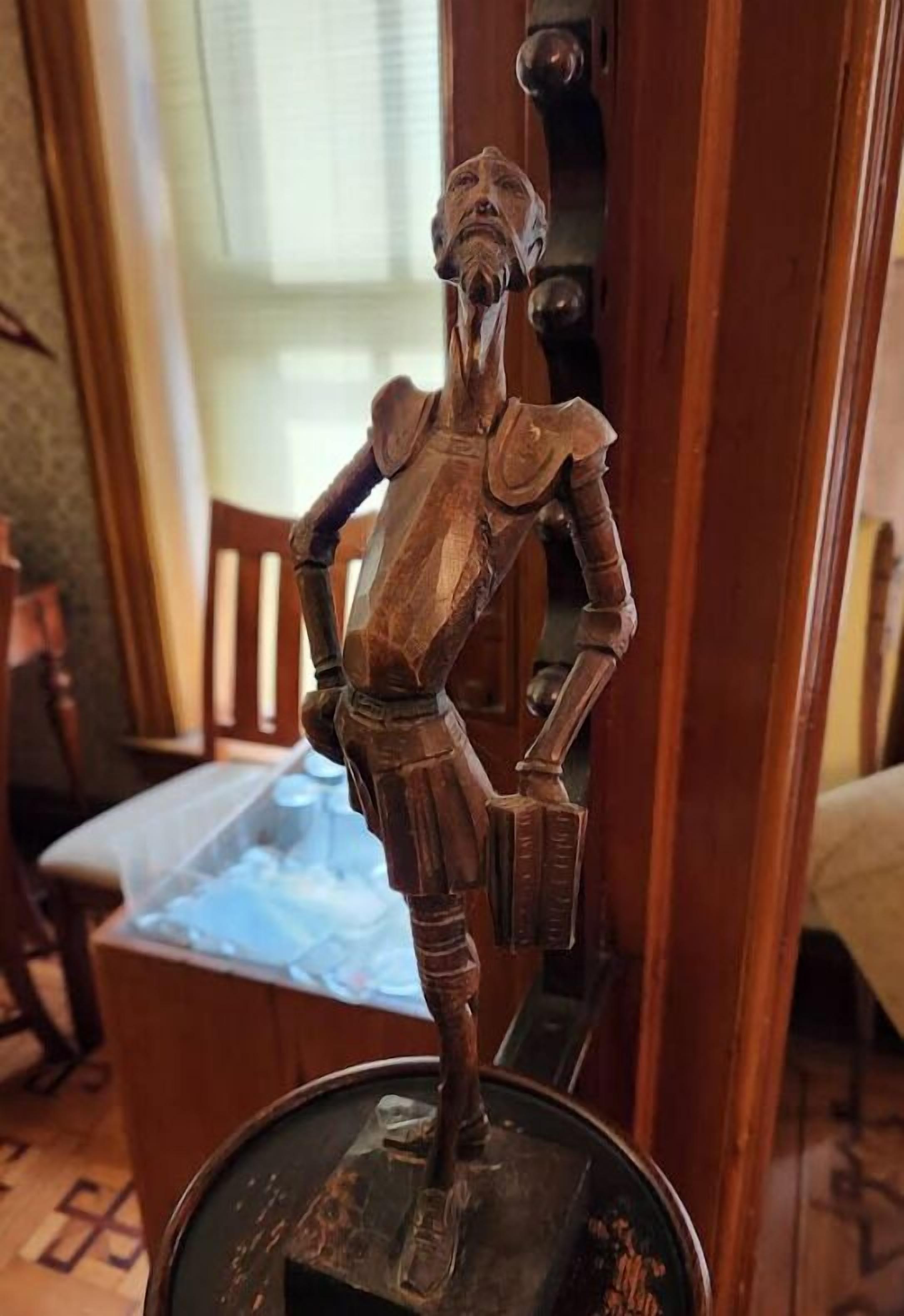 A wooden sculpture of a knight on a pedestal.