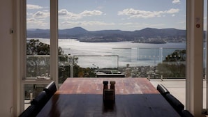 A dining area with a view of a body of water and mountains.