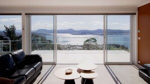 A spacious living room with a large sliding glass door leading to a balcony with a city view.