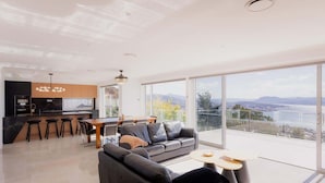 A modern living room with a sofa, a dining area, and a kitchen.
