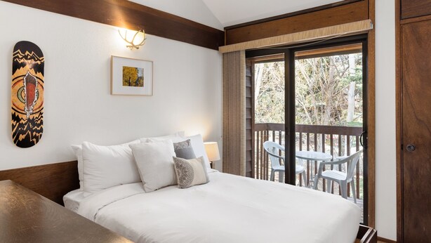 Une chambre à coucher avec un lit, un tableau encadré et une vue sur l’extérieur.