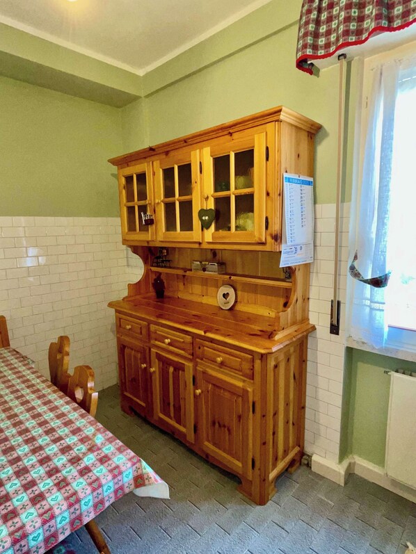 A kitchen with wooden cabinets, a checkered tablecloth, and a calendar on the wall.