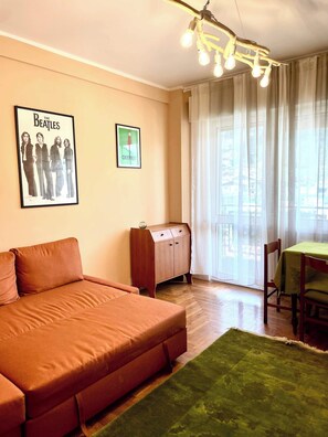 A living room with a sofa, a wooden cabinet, a table with a green tablecloth, and a window with curtains. - Cozy flat Pieve di Cadore (Pieve di Cadore)