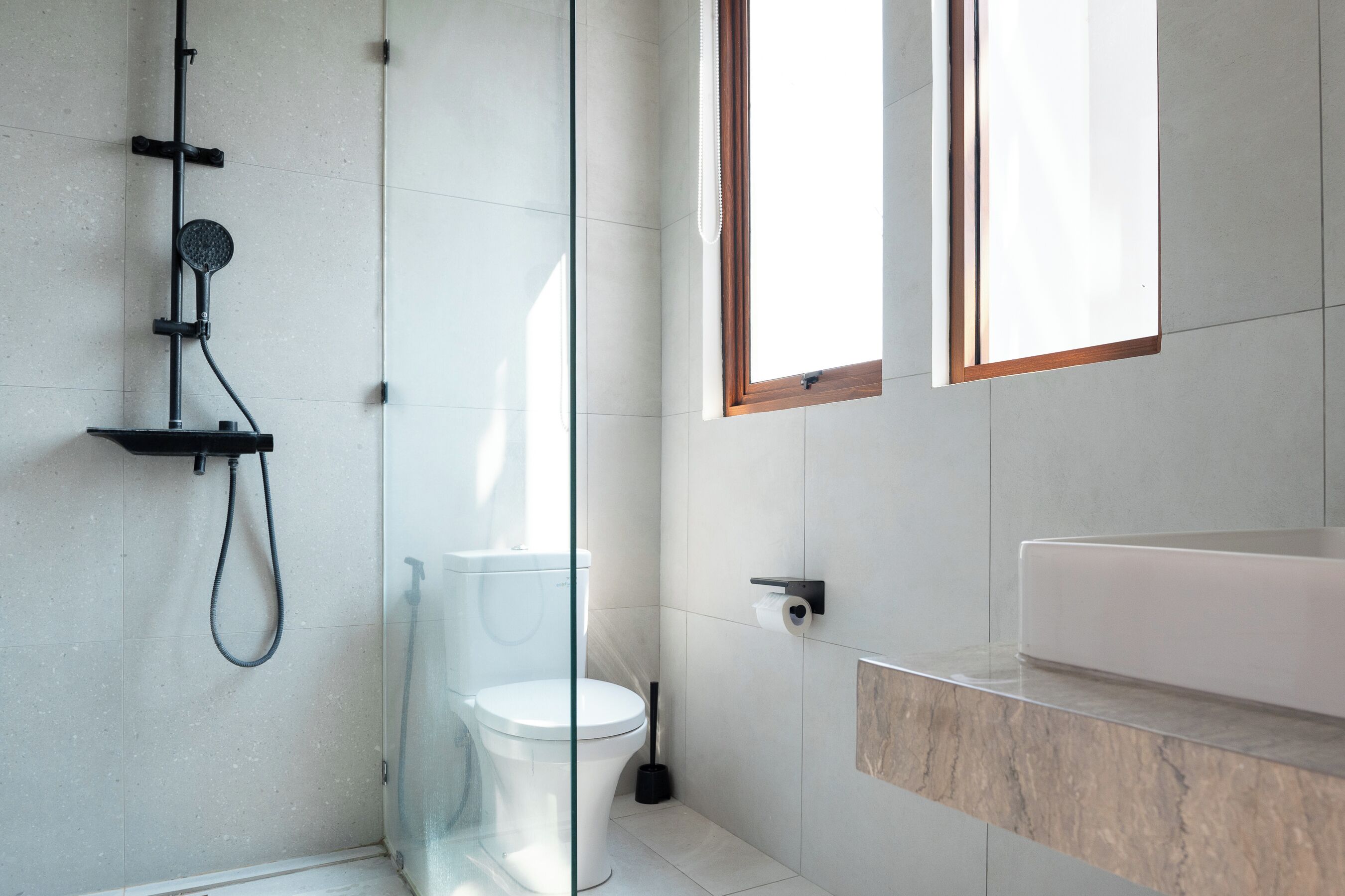 A modern bathroom with a glass shower enclosure, a toilet, and a vanity with a sink.