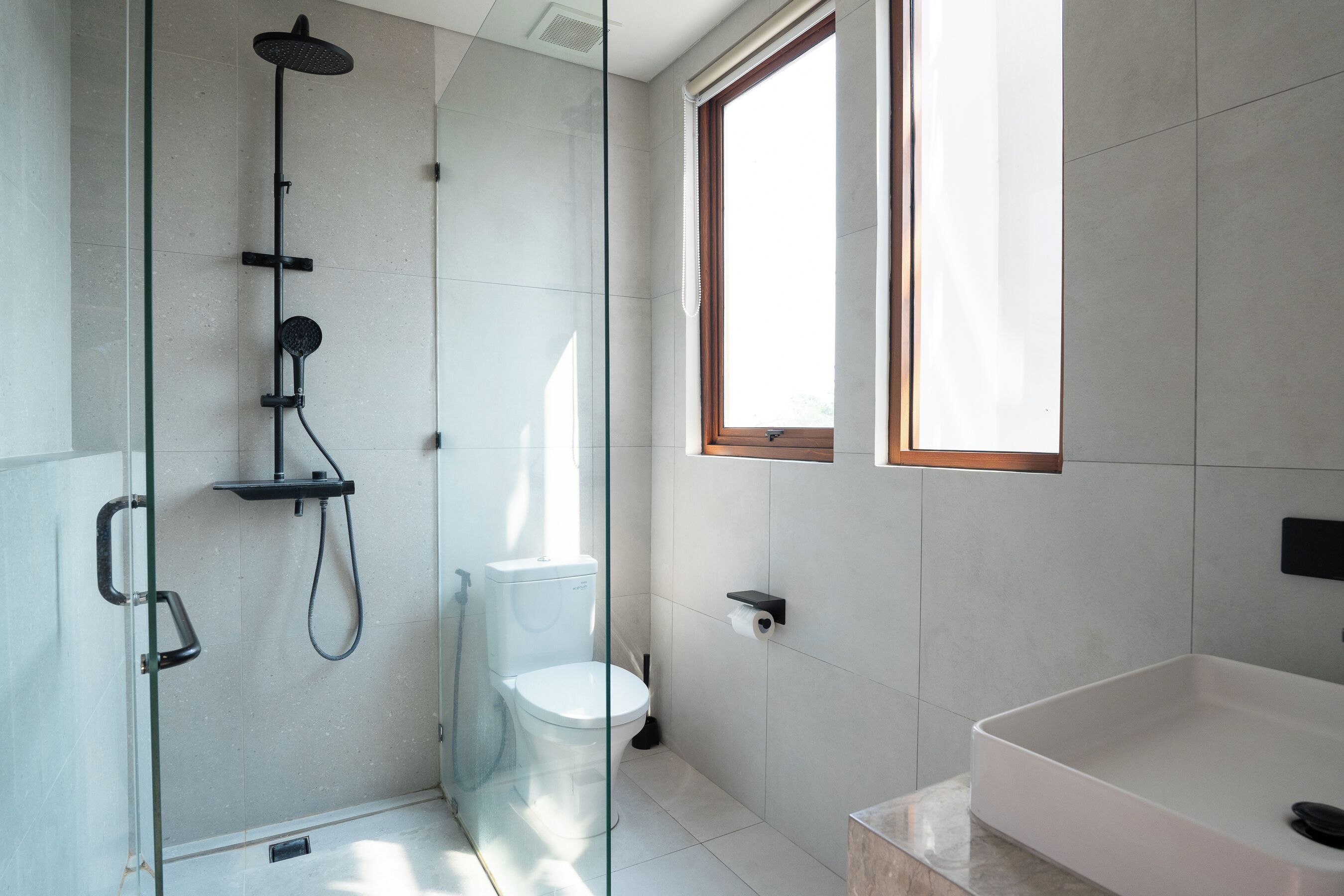 Un baño moderno con ducha de vidrio, inodoro blanco y una bañera grande.