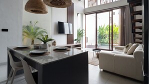 A modern living room with a sofa, a dining area with a table and chairs, and a TV mounted on the wall. - Lulu Villa - 2-bedrooms villa in Canggu (Canggu)