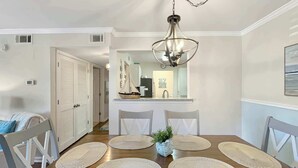 A dining area with a wooden table, four chairs, and a hanging light fixture. - $400 Free Activities, Pool, Pickle Ball, Tennis, Fitness Area! (Gulf Shores)