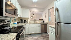 A modern kitchen with white cabinets, stainless steel appliances, and a granite countertop. - $400 Free Activities, Pool, Pickle Ball, Tennis, Fitness Area! (Gulf Shores)