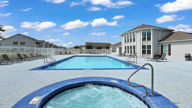 A swimming pool with a hot tub in the foreground, surrounded by lounge chairs and a building with a white exterior. - $400 Free Activities, Pool, Pickle Ball, Tennis, Fitness Area! (Gulf Shores)