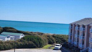 A beachfront building with a parking area and a white vehicle.